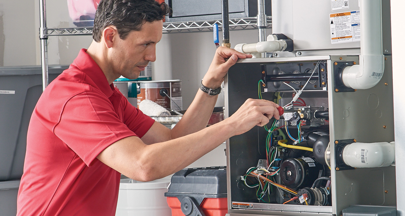 A man working on an electrical box in the kitchen.